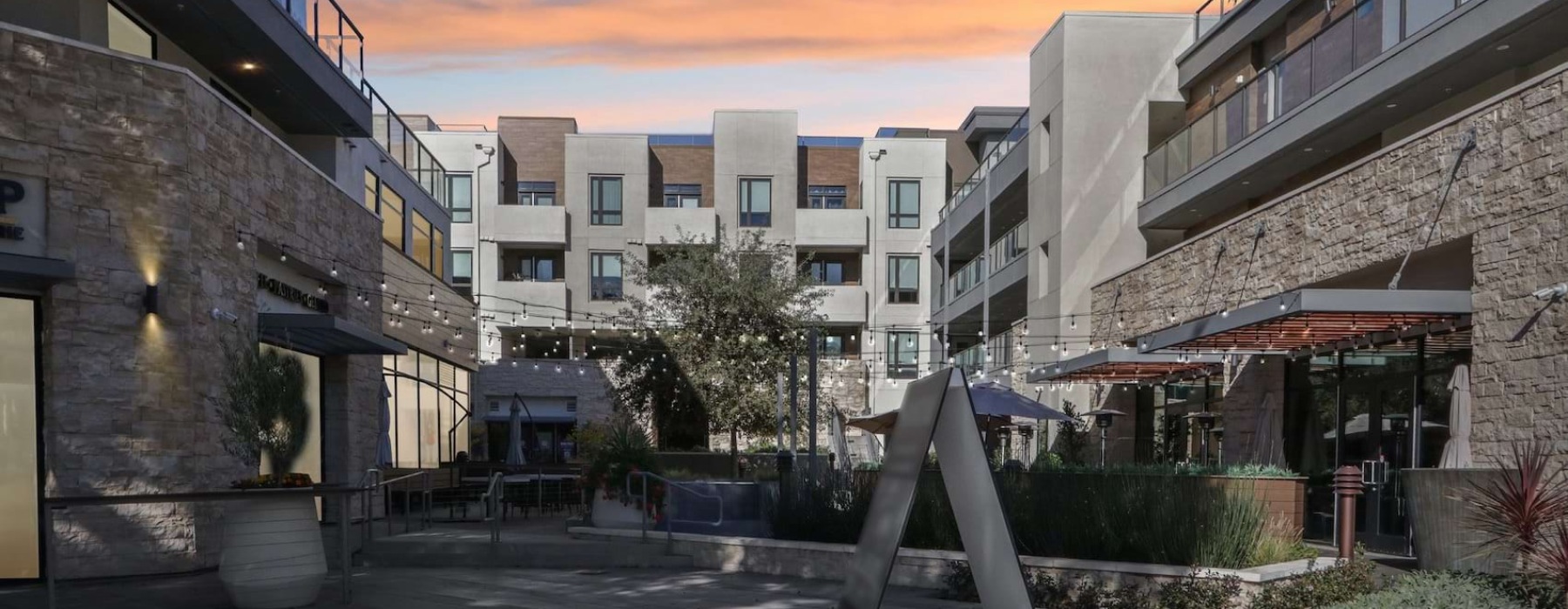 Santal Thousand Oaks courtyard buildings, balconies, string lighting, landscaped planters, and paved walkways at dusk.