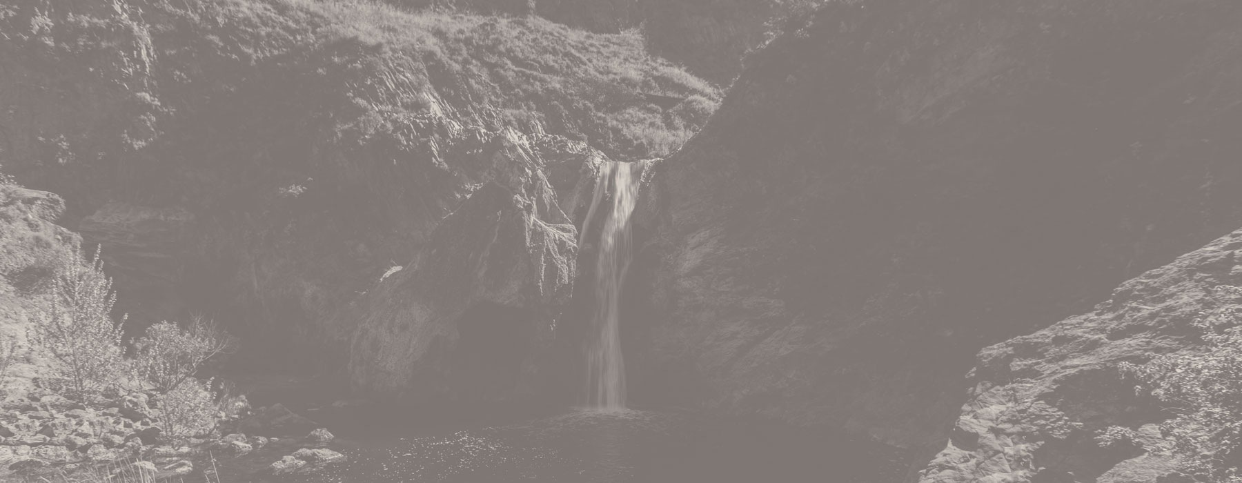 an image of a waterfall with a heavy grey color overlay over the image