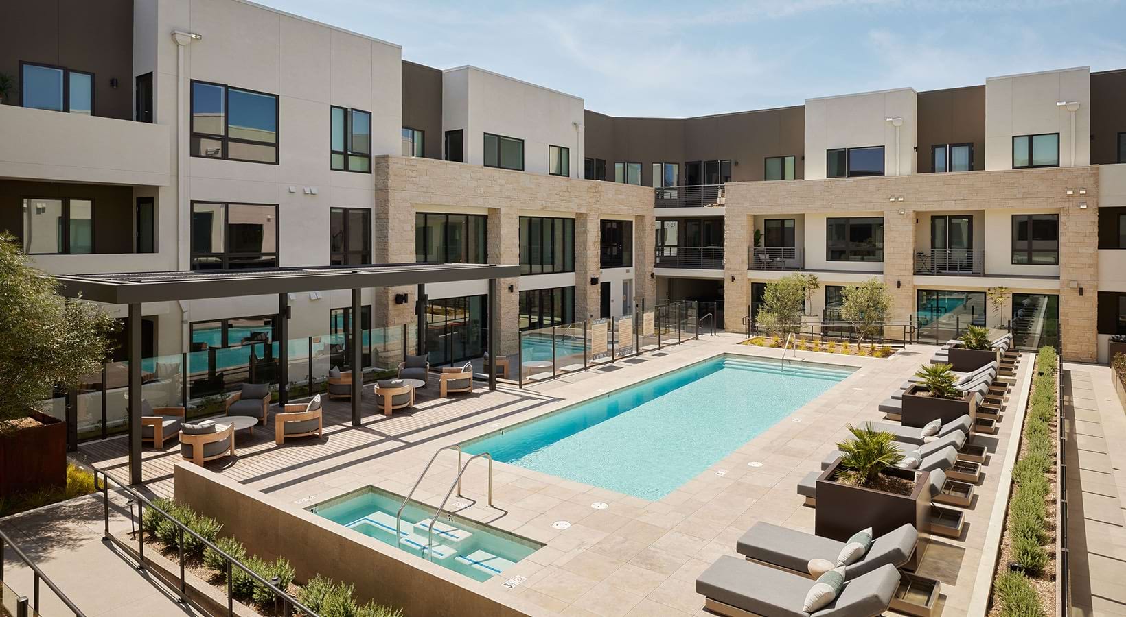 A resort-style pool courtyard with lap lanes, spa, pergola lounge seating, and modern balconies at Santal Thousand Oaks.